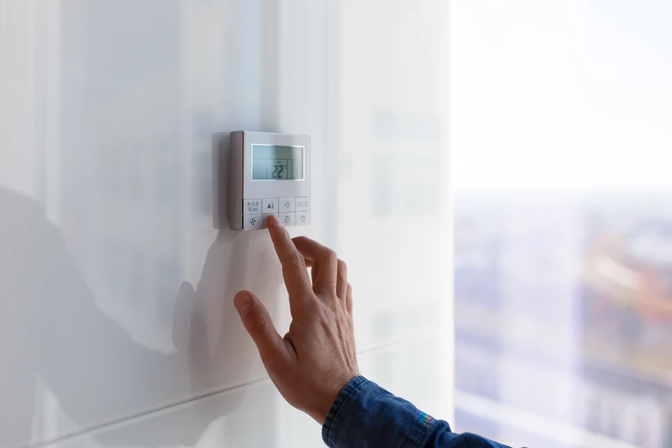Scène extérieure devant maison moderne avec deux professionnels discutant près d'une unité de climatisation