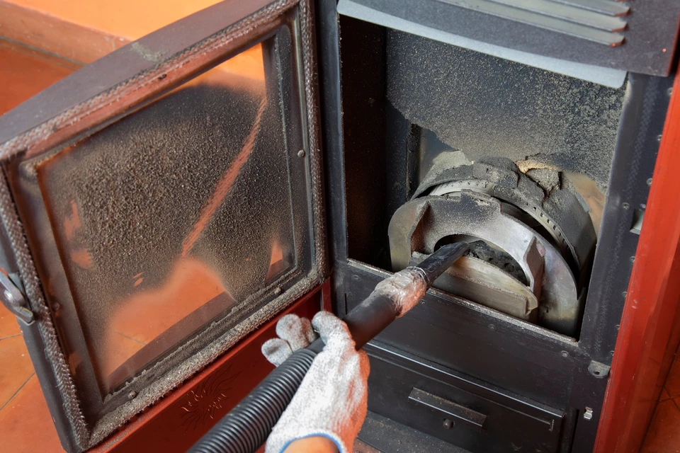 Technicien en salopette bleue effectuant la maintenance d'un radiateur à ailettes dans un intérieur résidentiel moderne