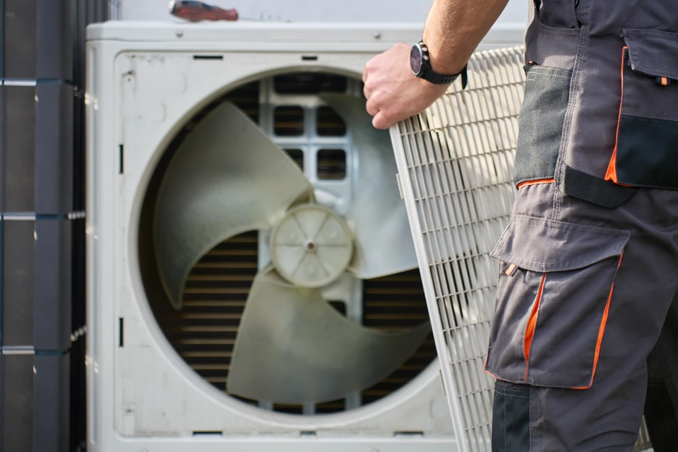 Un technicien en salopette ajuste une vanne sur une installation de chauffage en sous-sol