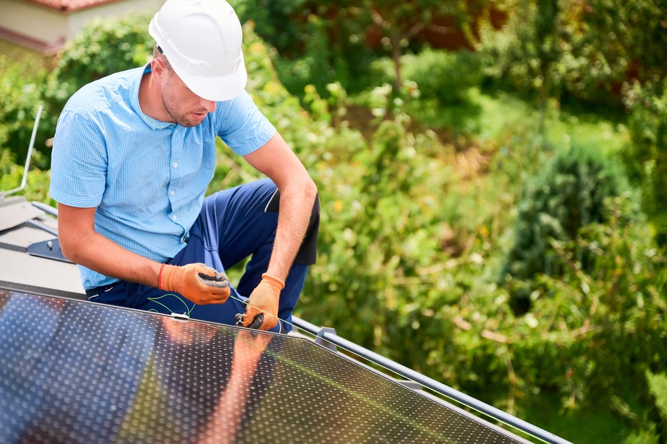 Installation de chauffe-eau solaire sur toiture métallique résidentielle sous ciel bleu nuageux